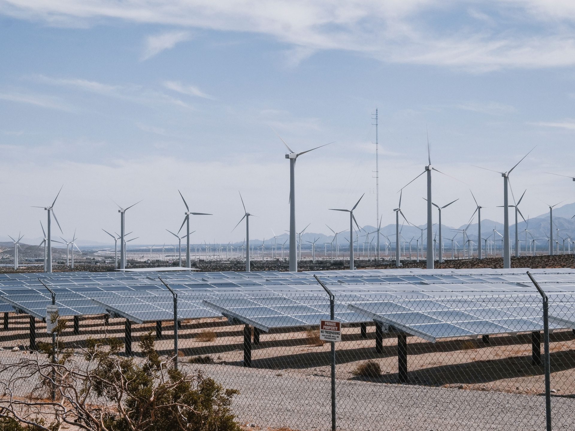 Ein Park für erneuerbare Energien mit Windkraftanlagen und Solarmodulen unter klarem Himmel.